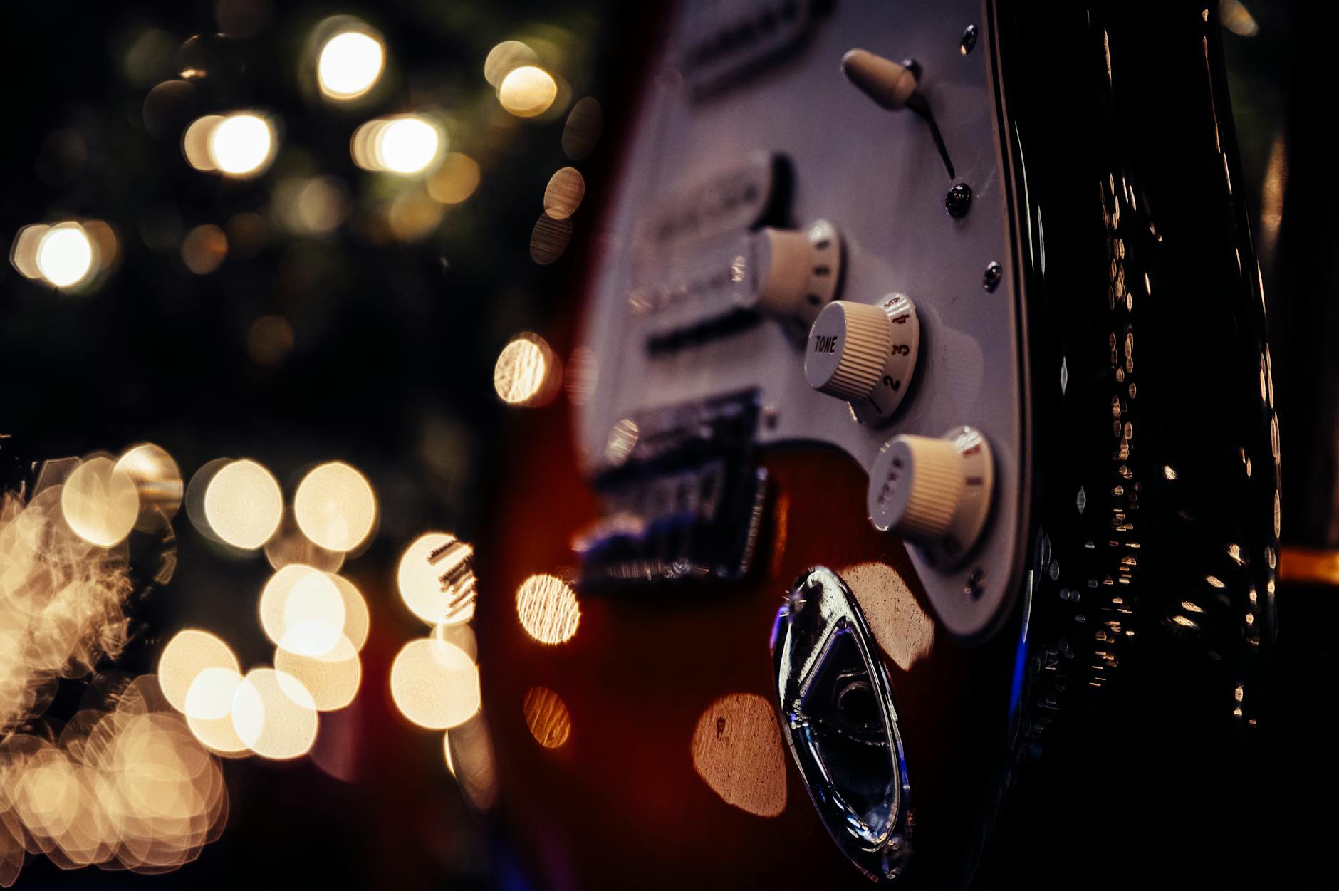 Zbliżenie gałek tonu na gitarze elektrycznej w świetle scenicznych lamp
