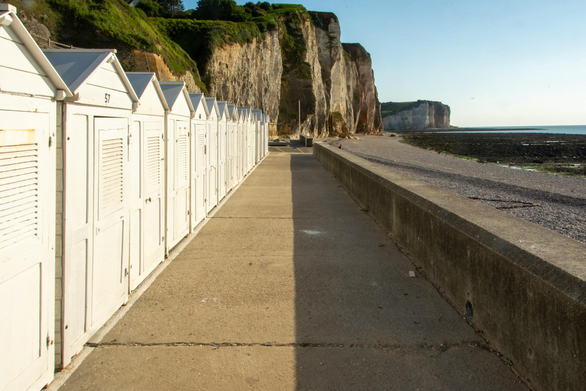 Białe domki plażowe u stóp jasnego klifu nad morzem